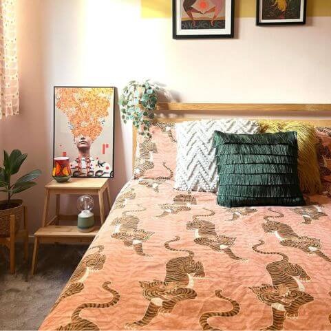 A double bed dressed with orange Tibetan tiger bedding and three textured scatter cushions.