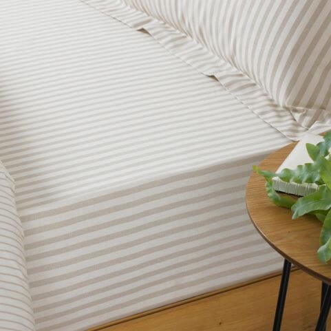 A white cotton bed sheet with a vertical striped pattern in a grey shade, made on a bed with matching pillowcases.