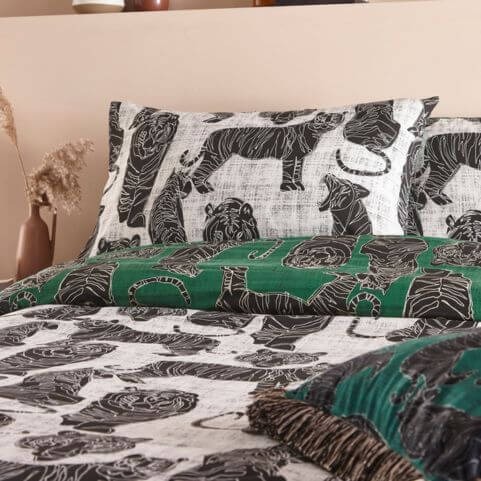 A jungle green duvet cover set with a printed tiger design, dressed on a bed to reveal the black and white reverse design.