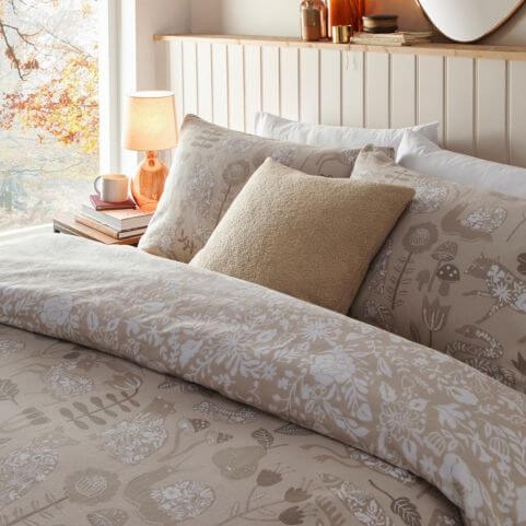 A brushed cotton duvet cover set with a folk-inspired printed design, arranged on a bed next to a decorated side table.