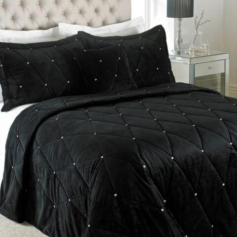 A quilted velvet bedspread with diamond stitching, embellished with diamante crystal sequins and arranged on a bed with matching pillowcases.
