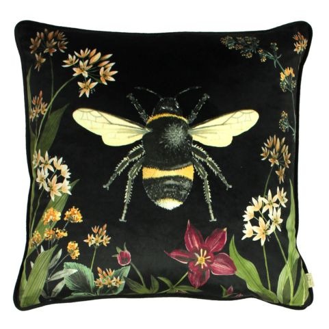 A black velvet cushion with a nature-inspired design of wildflowers and a bumblebee