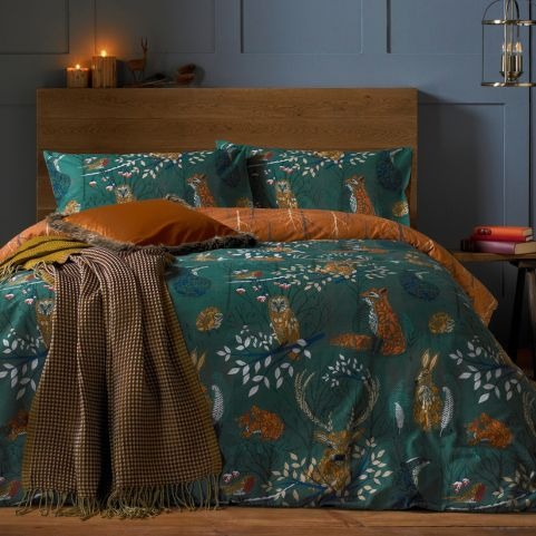 An emerald green duvet cover set with a nature-inspired autumnal design, featuring stags, hares, foxes and forest florals.