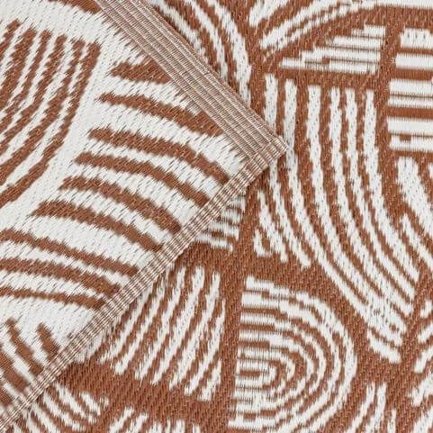 A closeup image of a waterproof outdoor rug made from 100% recycled polypropylene, with a printed abstract swirl design.
