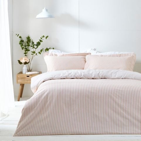 blush bedding set with a bedside table and a plant