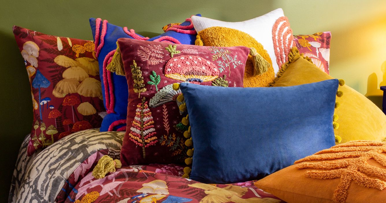 colourful maximalist bed with patterned cushions and throws