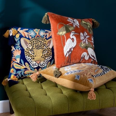 pile of maximalist coloured cushions on a chair