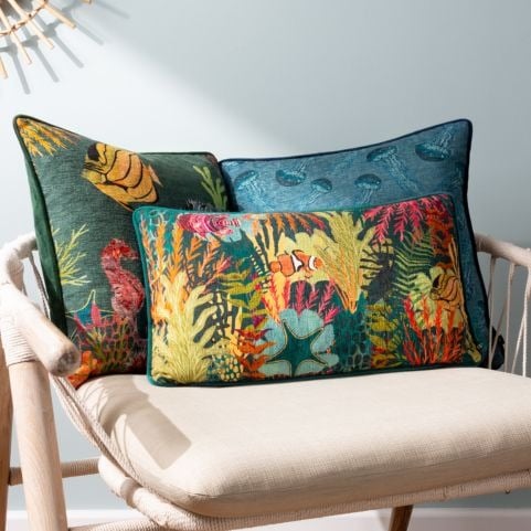 pile of cushions on a chair with 3 ocean-themed maximalist cushions