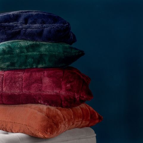 pile of faux fur luxury cushions in blue, green, red and rust