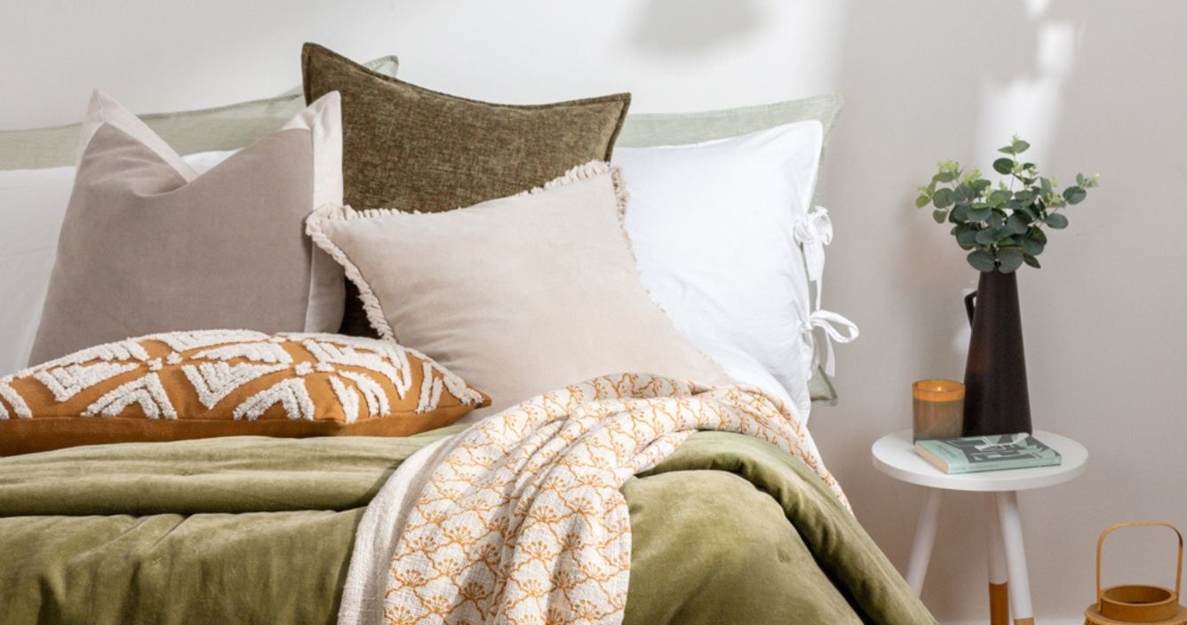 scandi style bed decor with neutral cushions and olive green throw on bed