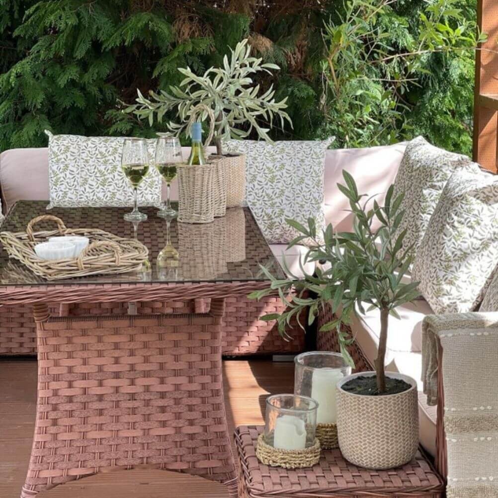 A deck sofa decorated with floral outdoor cushions in an olive green shade.