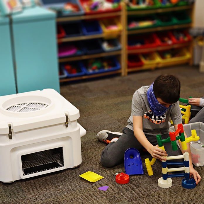 A QuFresh air purifier quietly works to improve indoor air quality in a large school room while children learn and play.