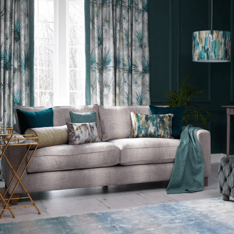Sofa cushions in a variety of colours and patterns, arranged on a grey sofa in a casual, contemporary style.