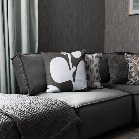 A selection of grey cushions arranged neatly on a corner sofa.