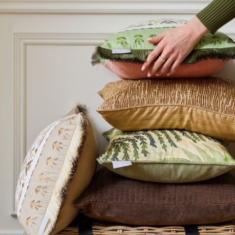 A collection of cushions piled on top of each other in autumn shades of green and brown