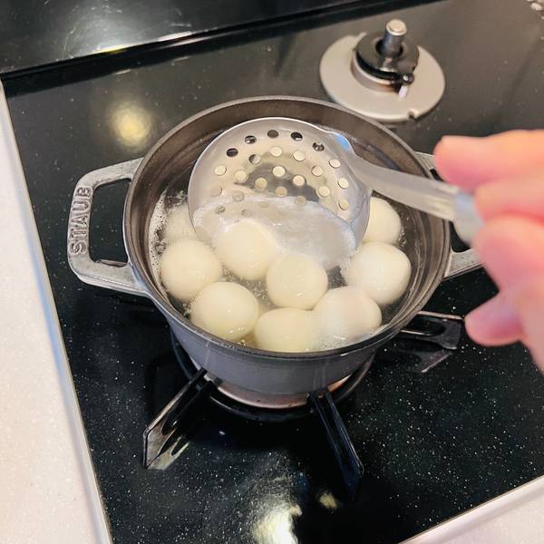 Taking the dango out of the boiling water with a skimmer spoon