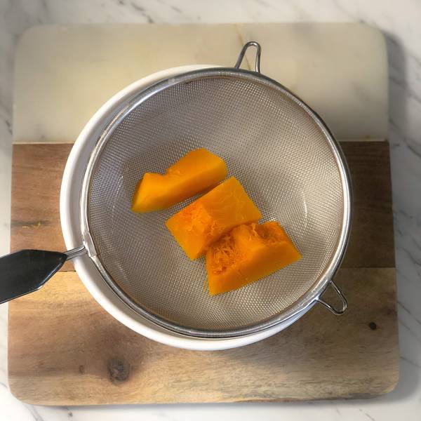 placing steamed kabocha pieces into a strainer