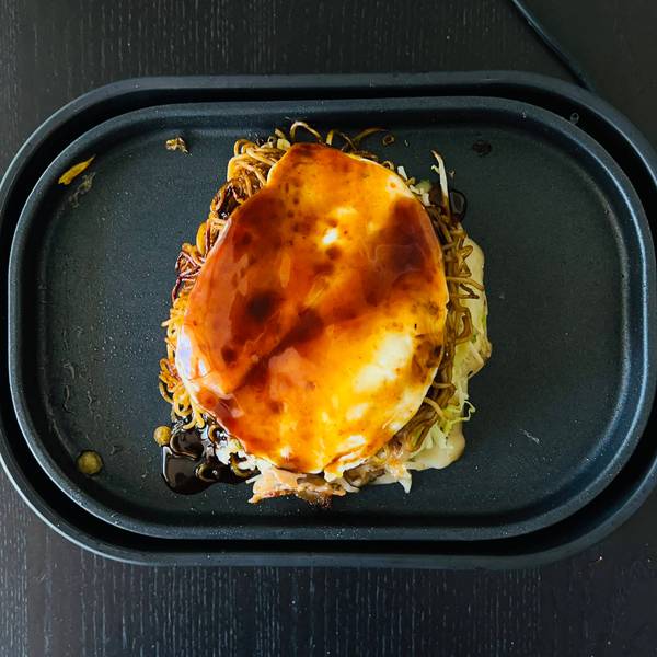 Topping the okonomiyaki with sauce