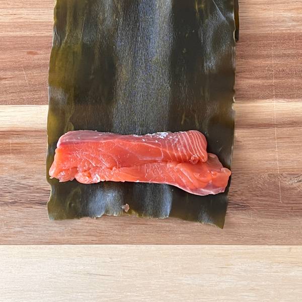 adding another piece of salmon, to make rolling the kombu easier