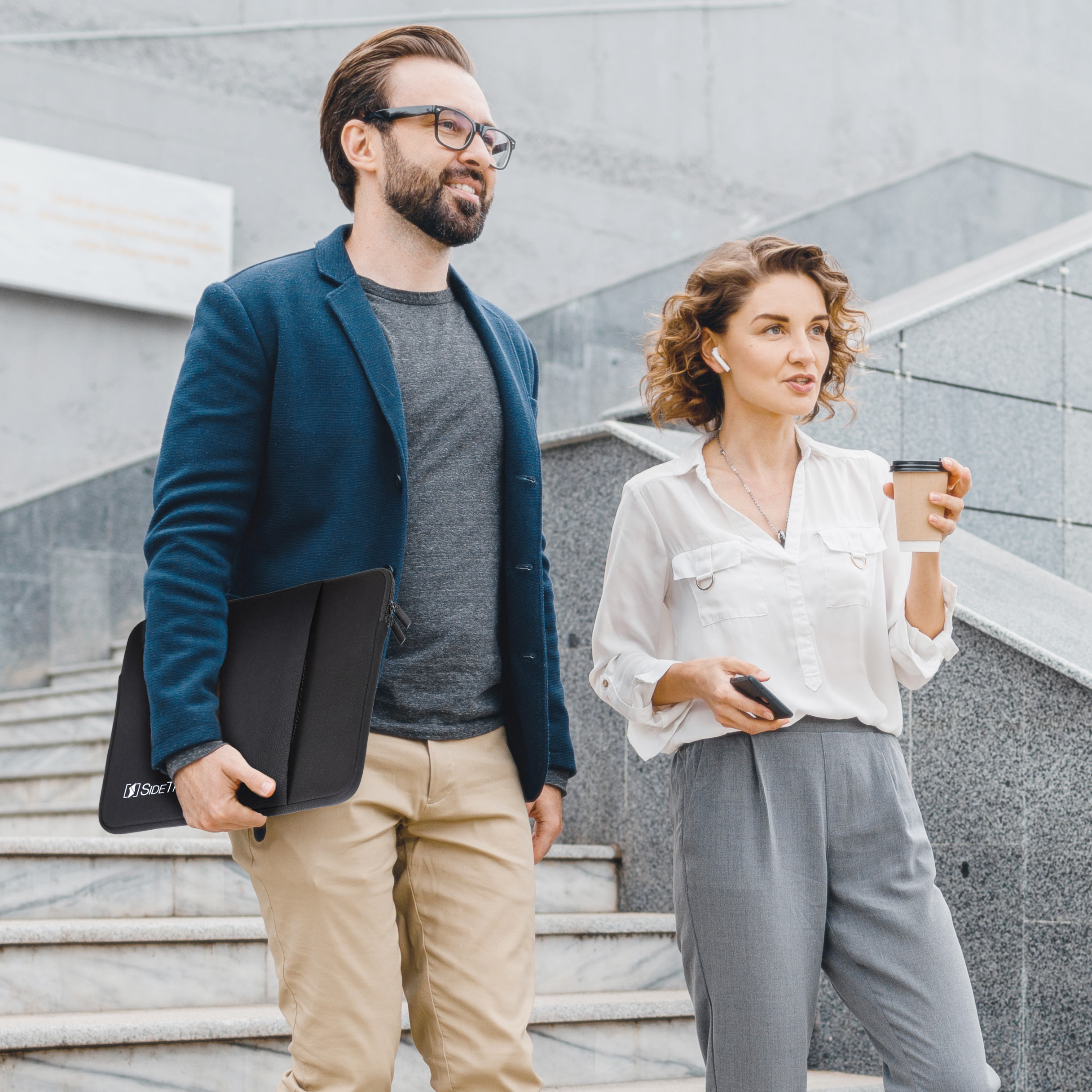 Two people walking down stairs. Man holding a Side track protective case.