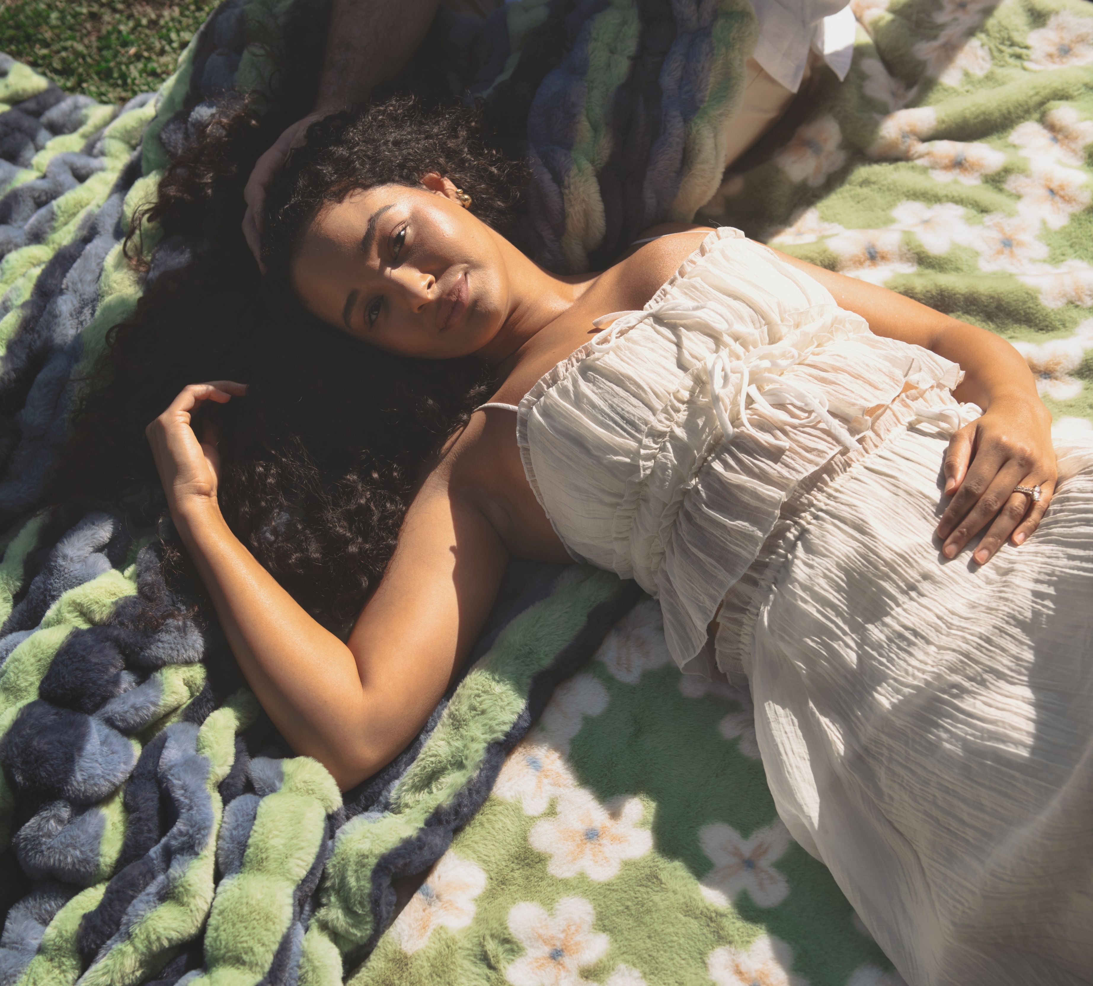 Woman relaxing with a soft spring blanket and layered floral textures for spring bedroom decor