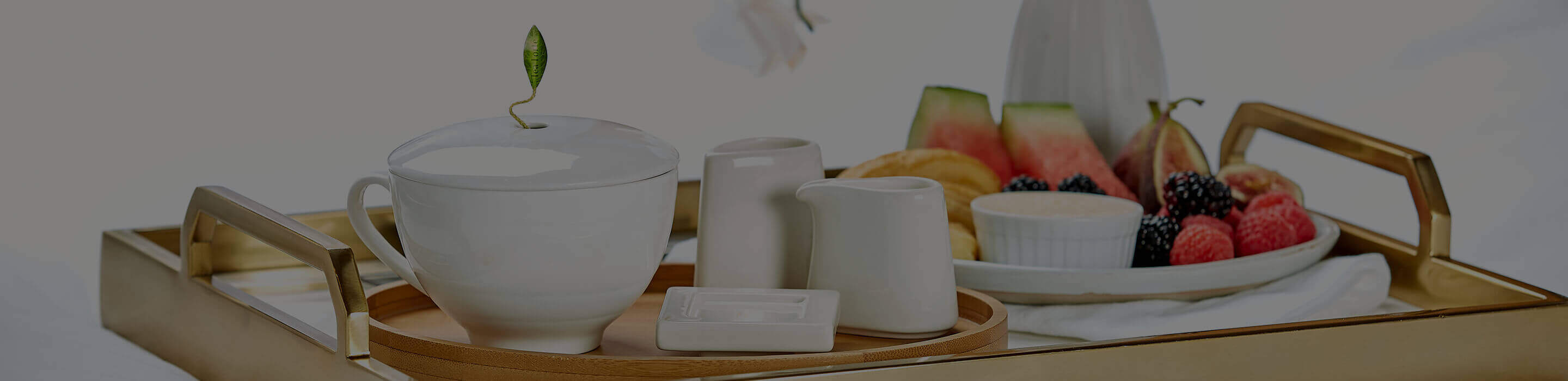 Café Cup on a tray on a bed with fruit and flowers, sugar and creamer