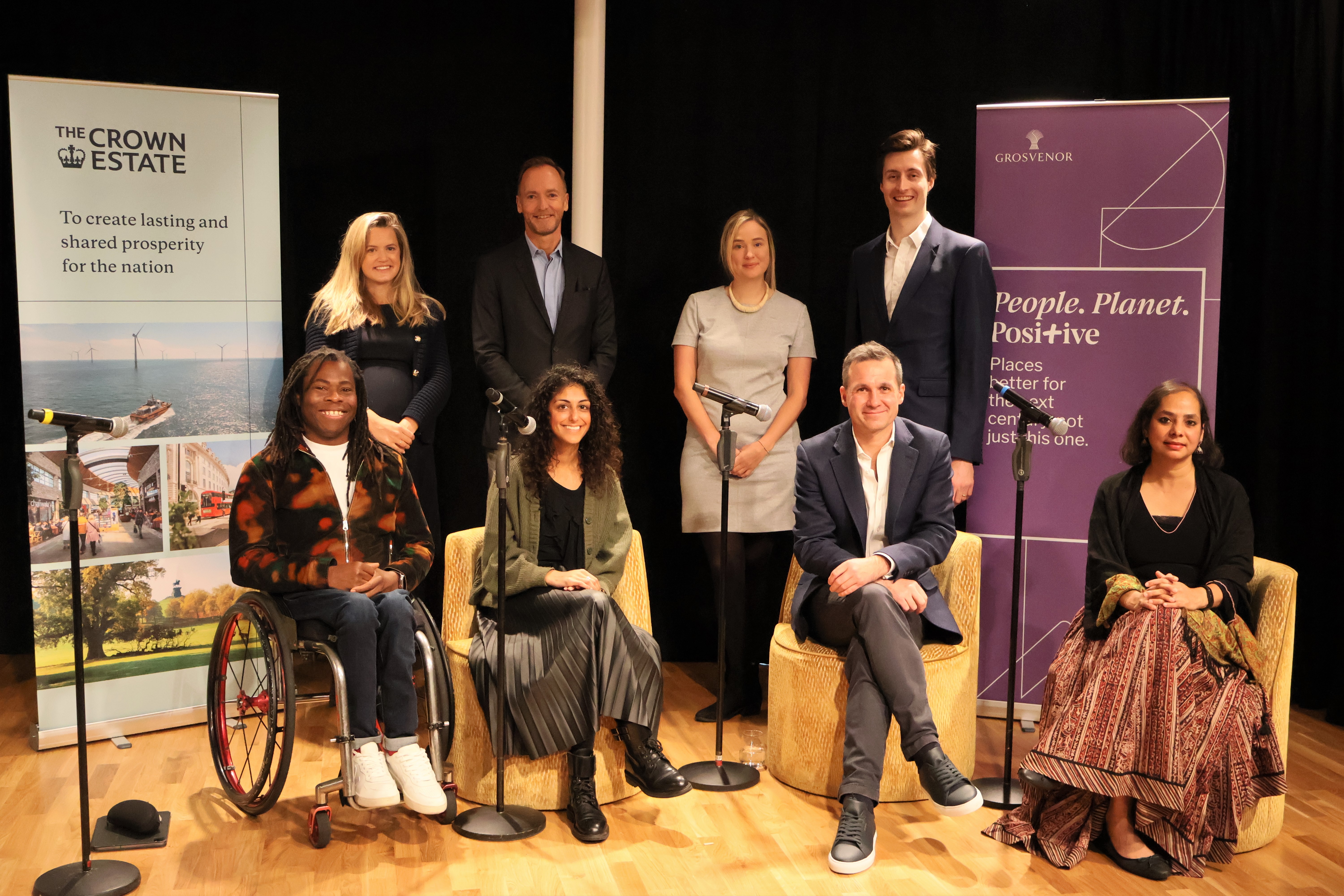 8 members of panel on stage at Inclusive Spaces and Places launch event, smiling facing camera