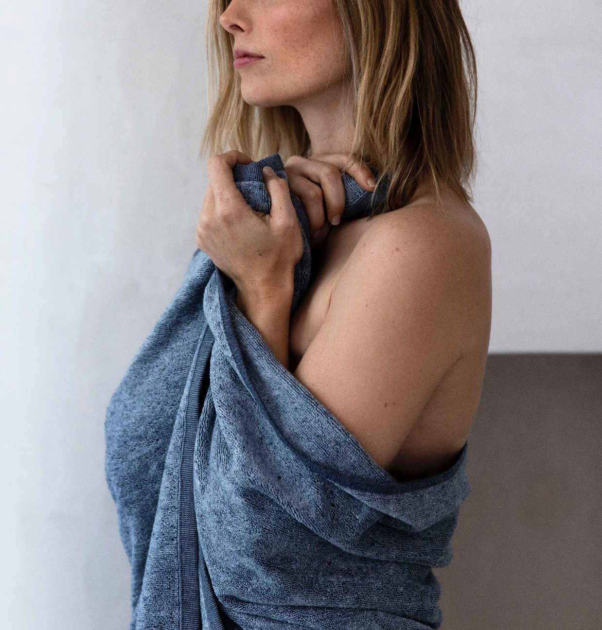 A model stands with the Denim Bath Towel wrapped around herself