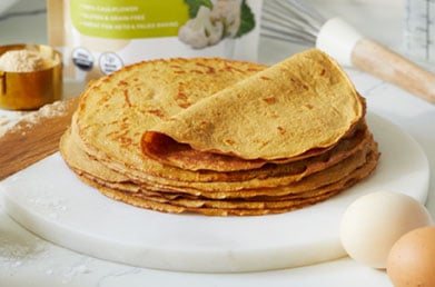 Stack of low carb tortillas made with Navitas Cauliflower Flour on plate next to fresh ingredients