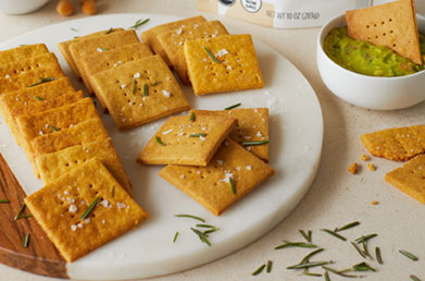 Plate of crackers made with Navitas Chickpea Flour sprinkled with fresh ingredients