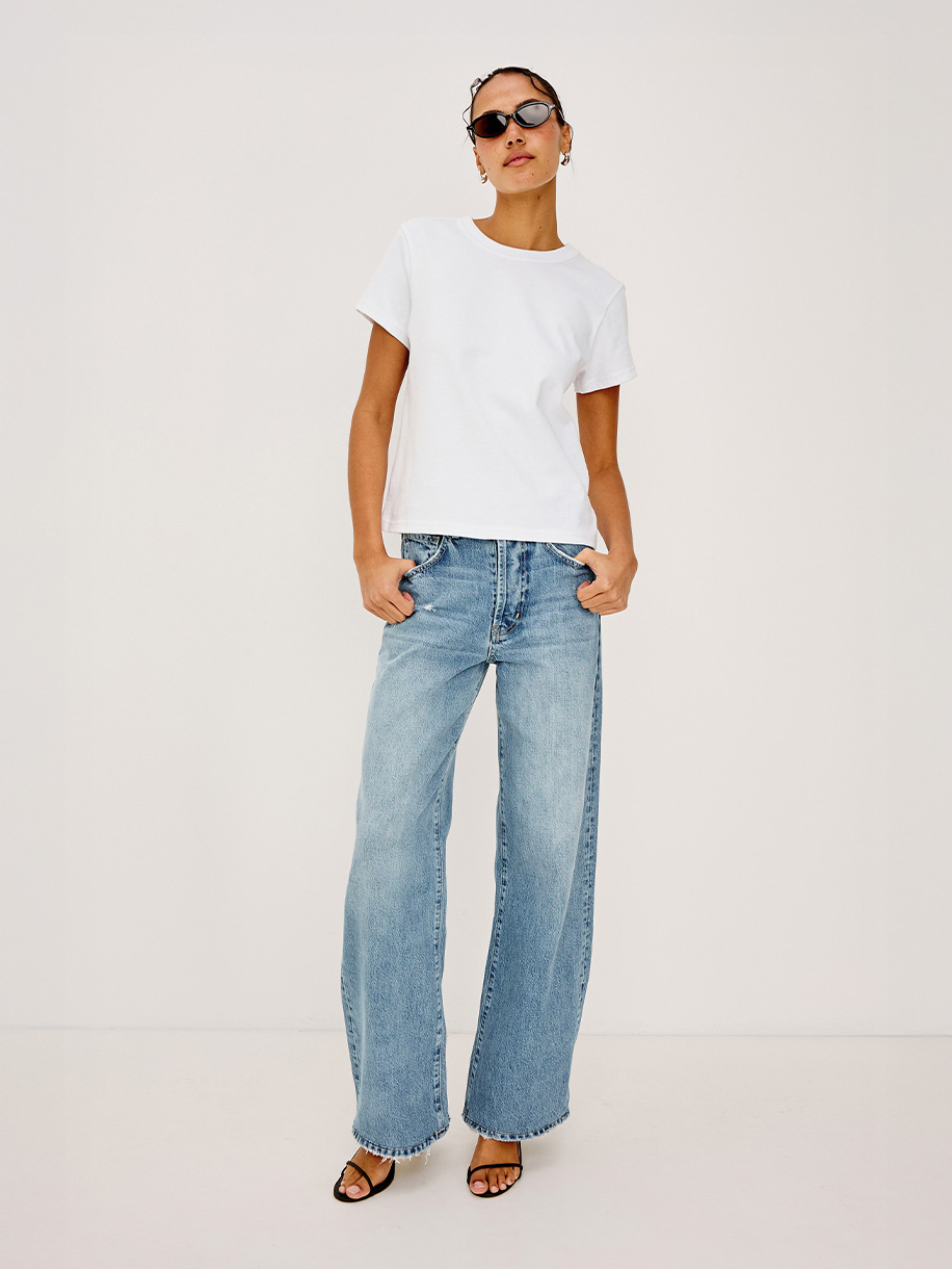 Woman in barrel fit jeans on white background. Click here to shop Barrel and Arc Fit Jeans