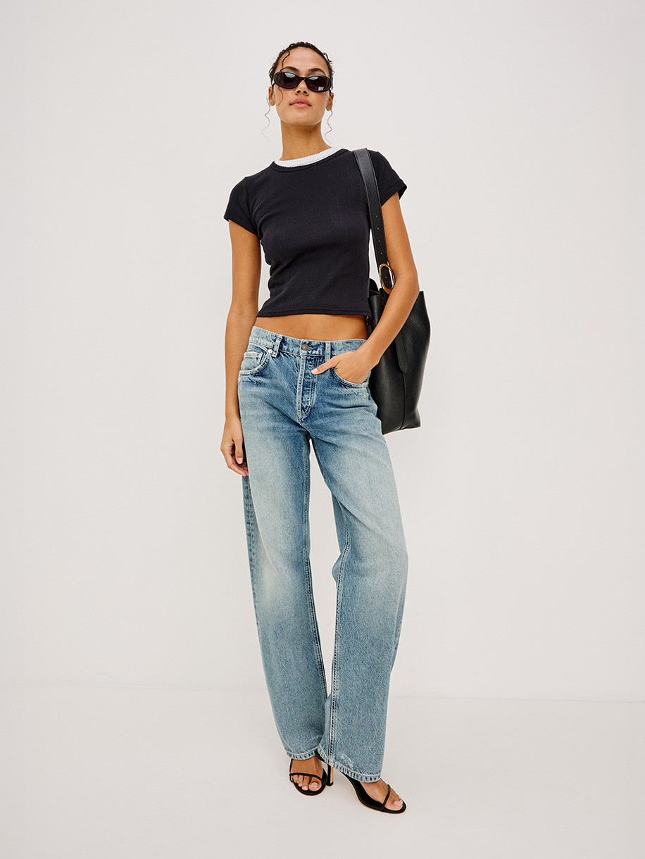 Woman in boyfriend fit jeans on white background. Click here to shop Boyfriend Fit Jeans
