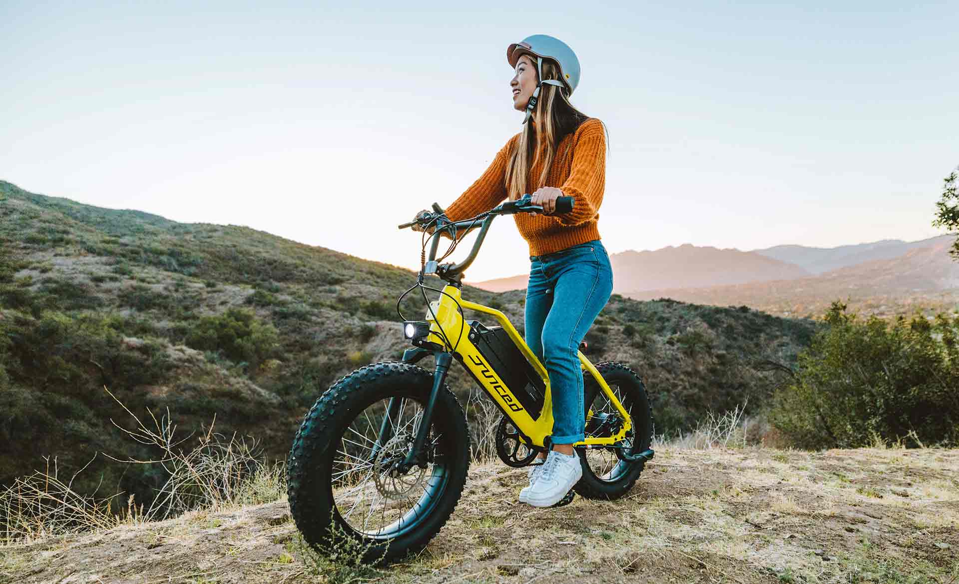 woman in orange sweater sitting on yellow juiced ripracer