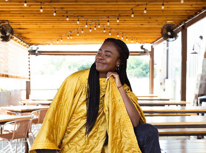 Woman wearing Field Blanket Printed in poncho mode. Blanket is sand color with cactus print.