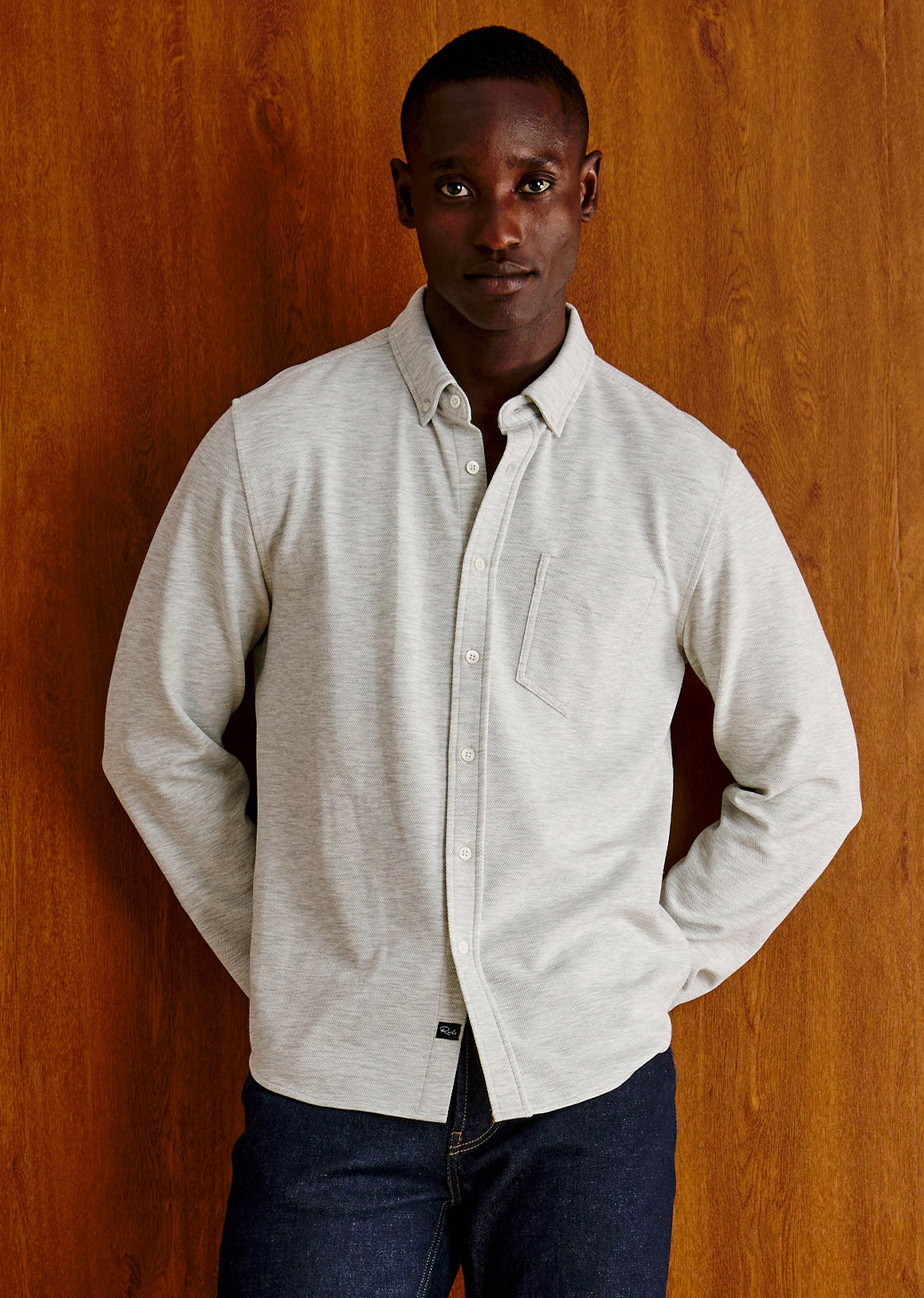 Man wearing a white long sleeve shirt against a brown background.