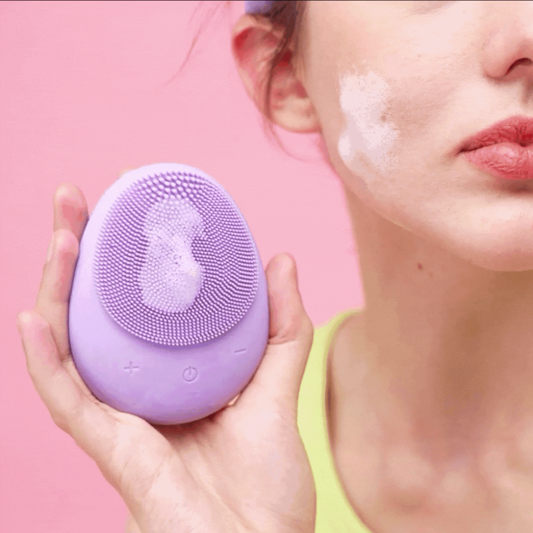 woman using the isla sonic facial cleansing brush in lavender to clean her skin