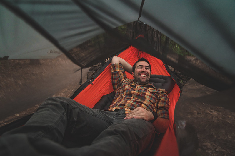 Man laying down on Pongo insulated camp sleeping pad in a in Kammok Mantis all-in-one hammock tent.
