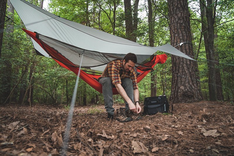 Man sitting in Kammok Mantis all-in-one hammock tent with Pongo Sleeping Pad attached inside of camping hammock.