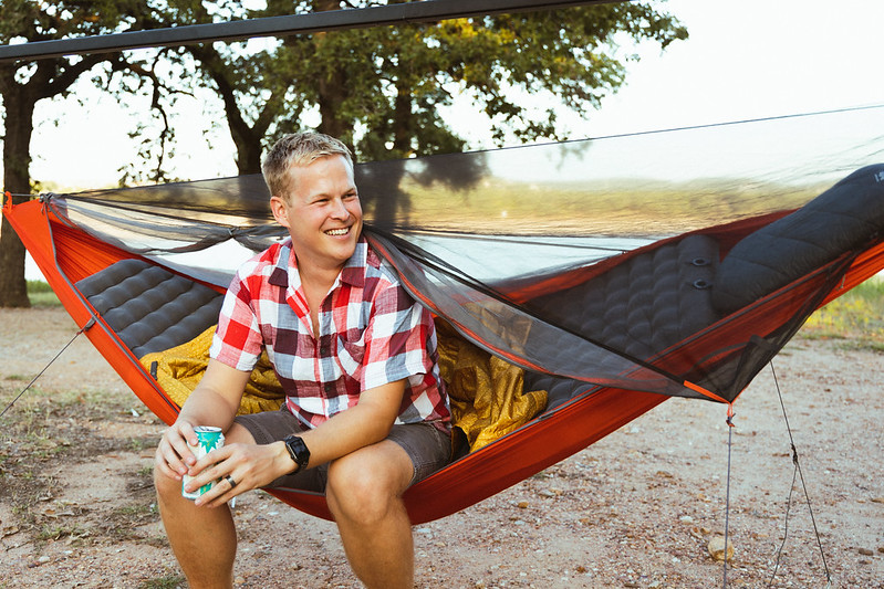 Man sitting in Kammok Mantis all-in-one hammock tent with Pongo Sleeping Pad attached inside of camping hammock.