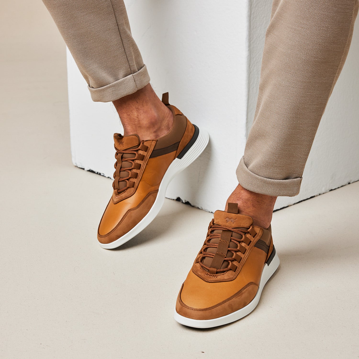 Knee down of a man seated wearing Crossover Victory Trainer in honey / white.