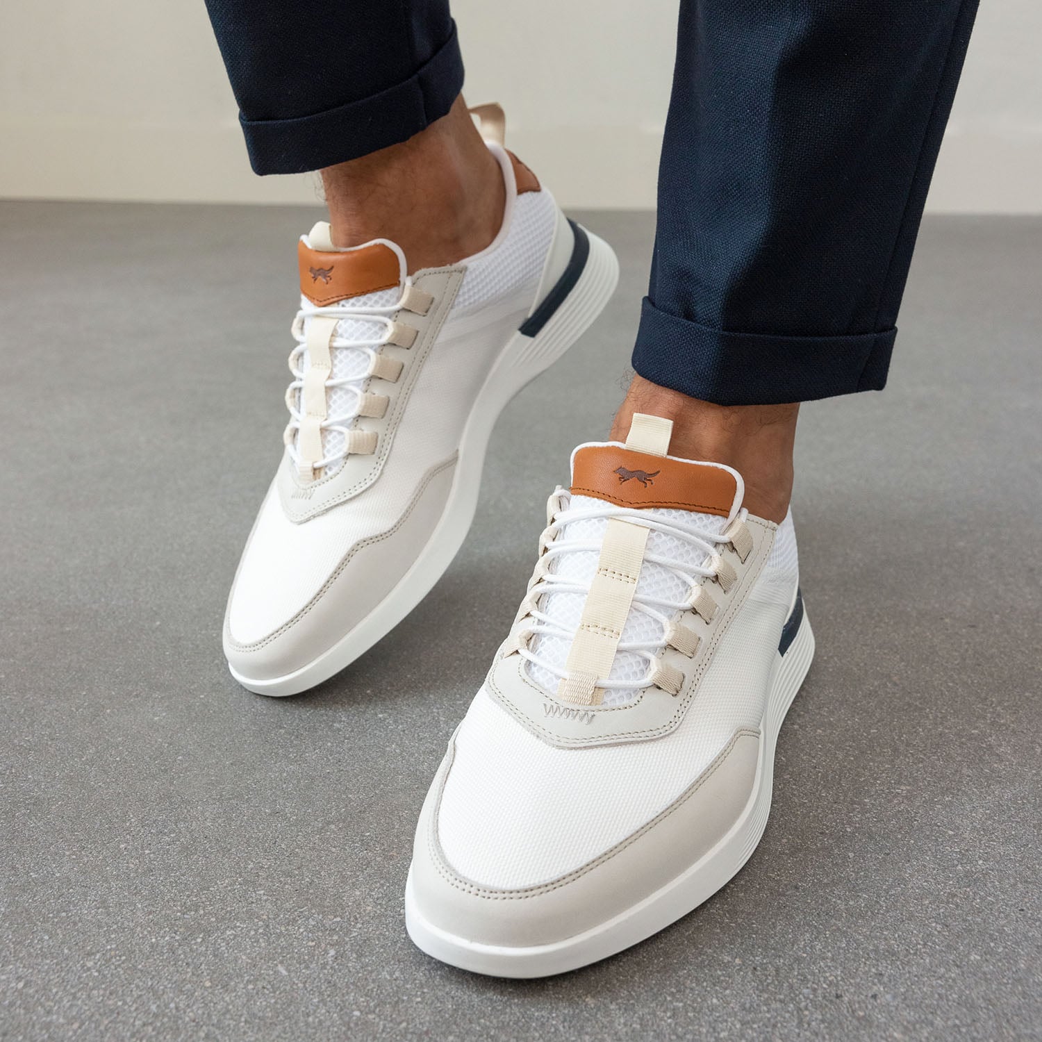 Knee down view of person sitting on chair wearing Crossover Victory Trainer in White