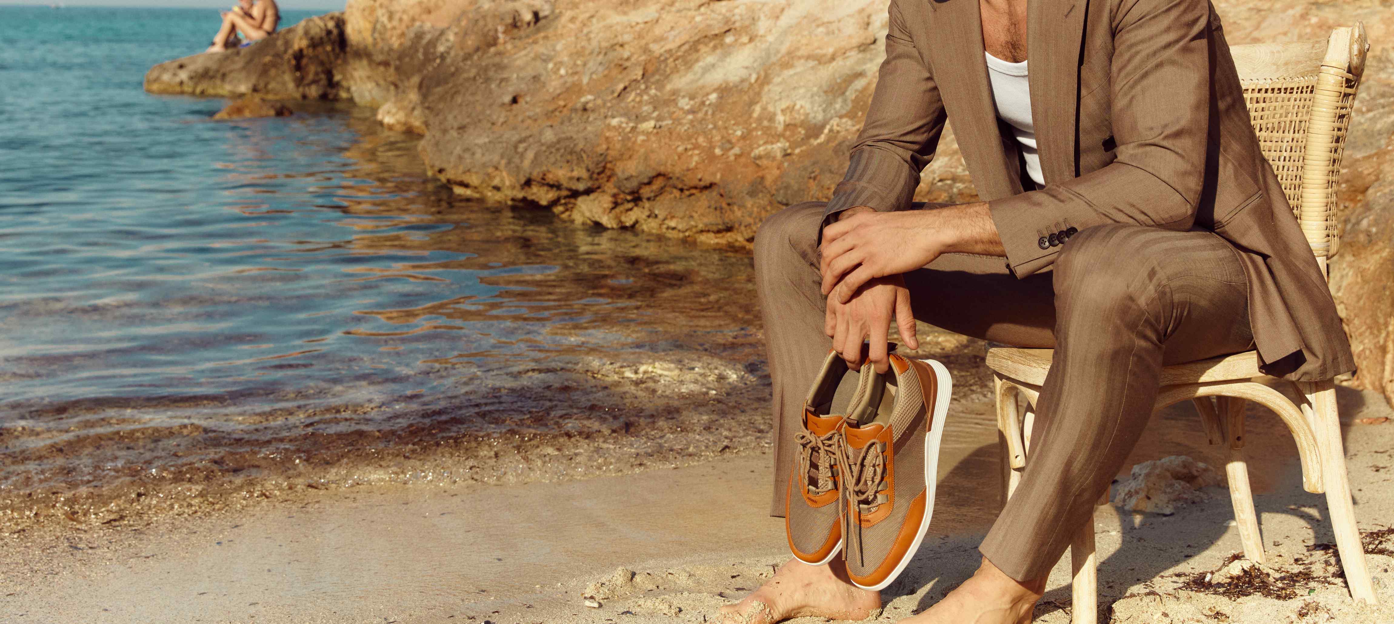 Man sitting on chair at the beach holding crossover victory trainer