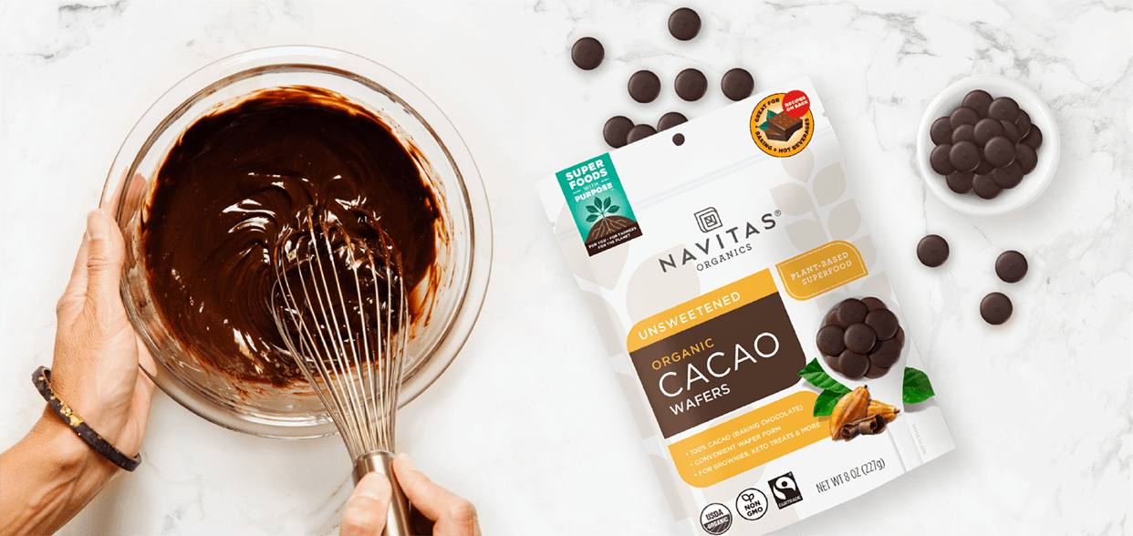 A woman mixing a bowl of brownie batter next to a bag of Navitas Organics Unsweetened Cacao Wafers