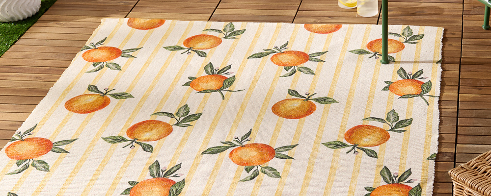 An outdoor rug with yellow stripes and orange designs