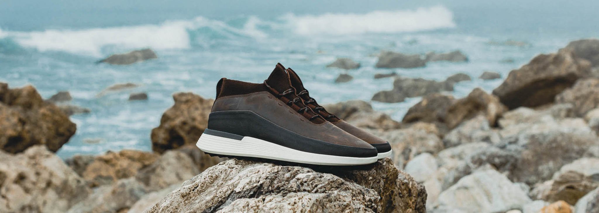 Side view of Men's Boot Crossover Mid WTZ in Brown on a rock with the ocean in the background