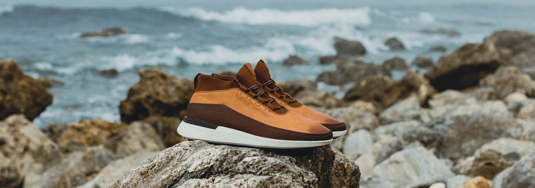 Side view of Men's Boot Crossover Mid WTZ in Honey on a rock with the ocean in the background