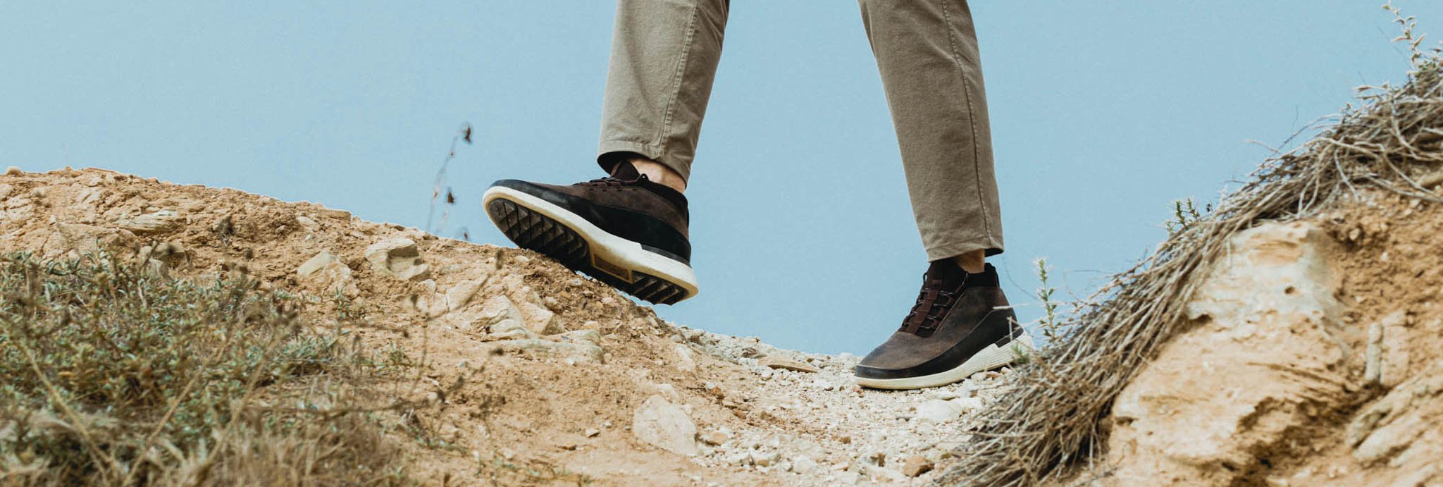 Knee down image of a man walking on a rocky terrain wearing Men's Boot Crossover Mid WTZ in Brown