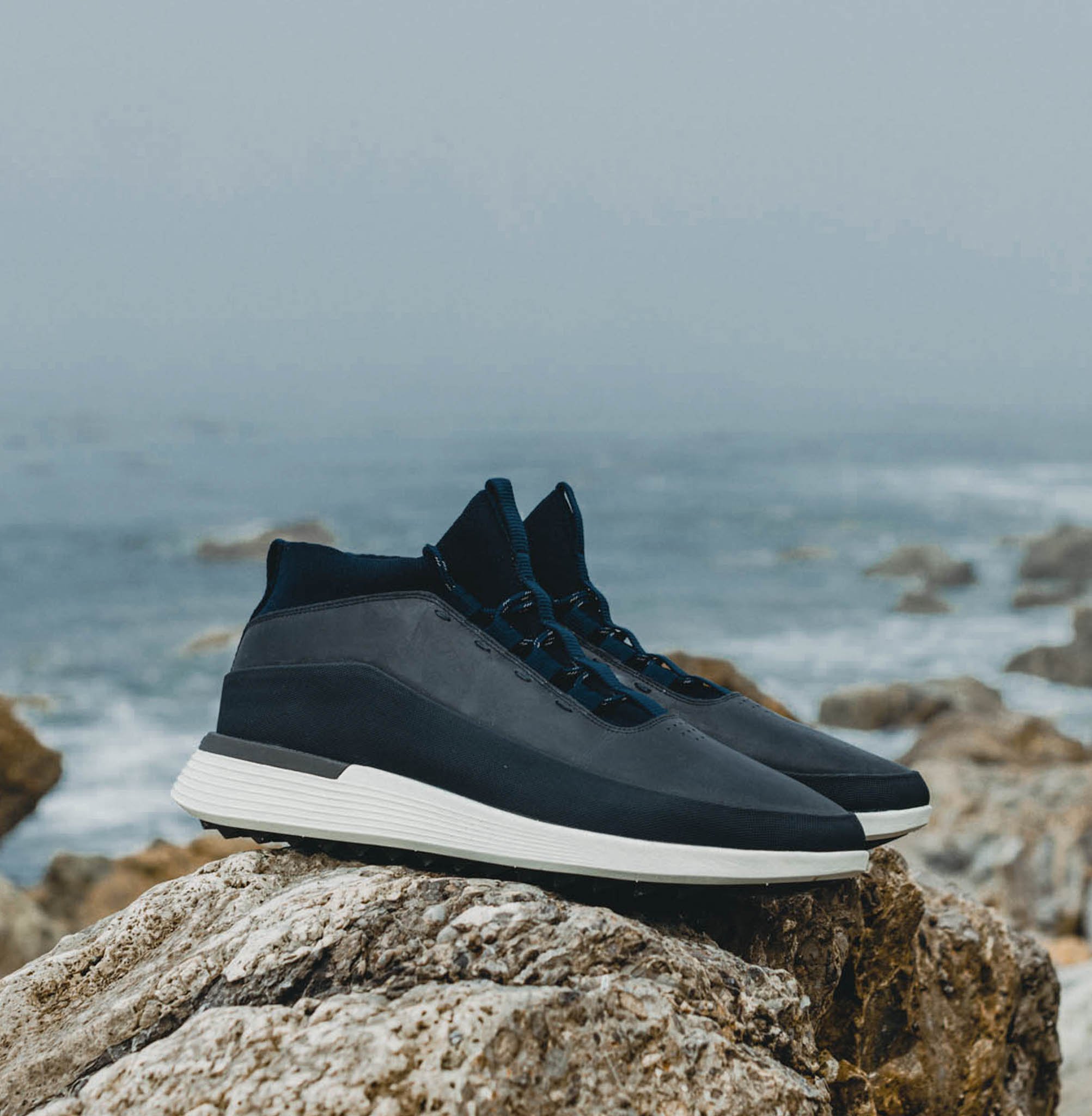 Side view of Men's Boot Crossover Mid WTZ in Navy on a rock with the ocean in the background
