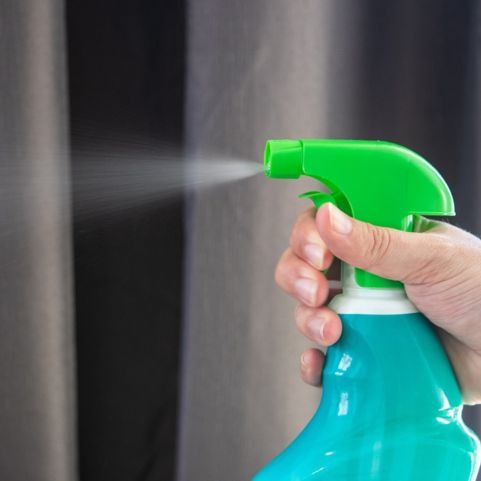 cleaning solution for blinds sprayed on grey fabric