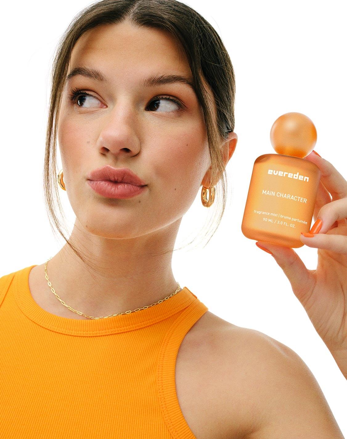 Woman holding orange fragrance bottle
